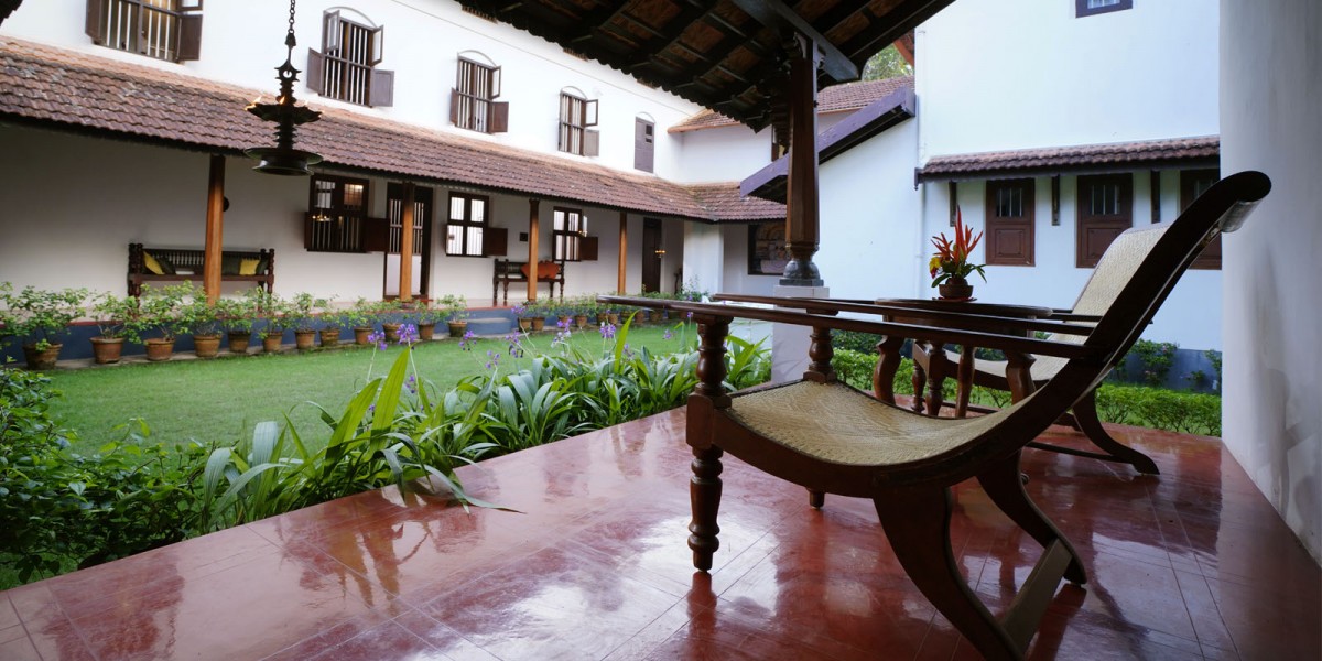 The veranda at Harivihar — a planter's chair on the polished red-oxide floor, opening onto the courtyard garden