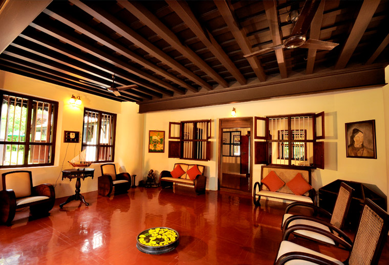 The poomugam — Harivihar's reception hall, with exposed teak-beam ceiling, red-oxide floor and antique planter's furniture